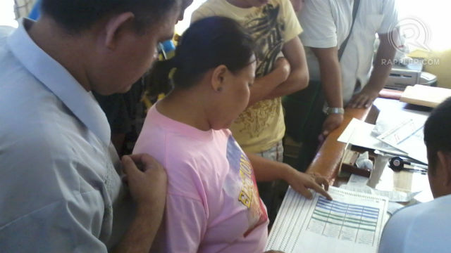 PREPPING UP. Tagbilaran Comelec chief Atty. Jonas Biliran (left) and poll watchers review the list of voters in Manansa Elementary School.