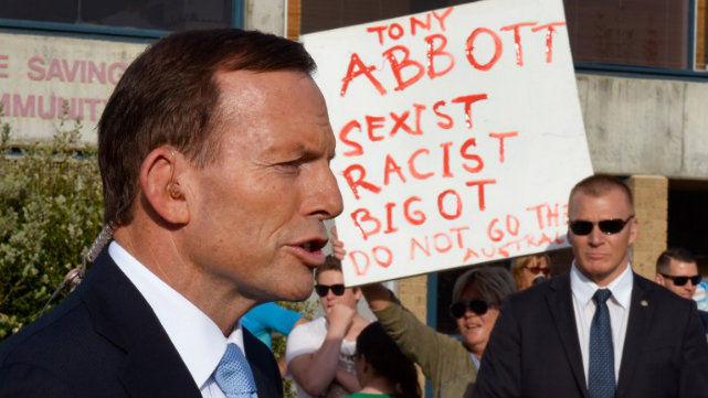 LANDSLIDE WIN? Australia's conservative Coalition leader Tony Abbott speaks to the media as a protester holds up a placard as polls open in the country's general election. Photo by AFP 