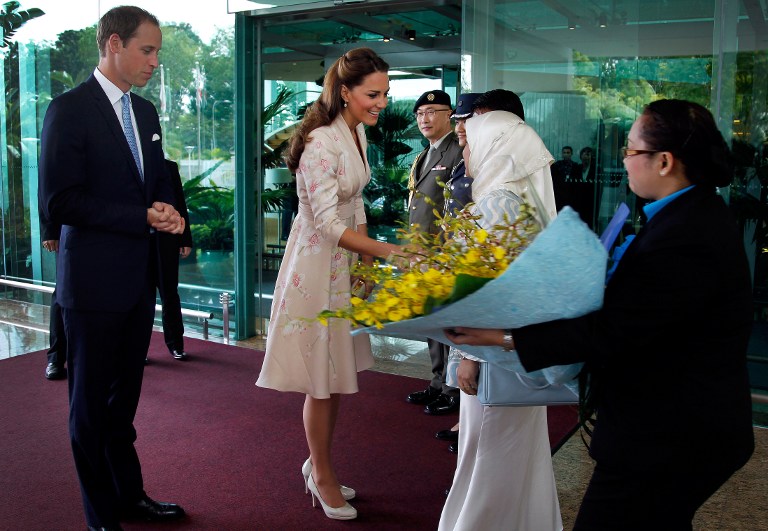 WILLIAM & KATE IN SINGAPORE. Britain's Prince William (L) looks on as his wife Catherine (C) receives flowers upon their arrival at the VIP terminal of Changi International Airport in Singapore on September 11, 2012. The couple arrived in Singapore to kick off a nine-day Southeast Asian and Pacific tour marking Queen Elizabeth II's Diamond Jubilee. AFP PHOTO / POOL / Wong Maye-E