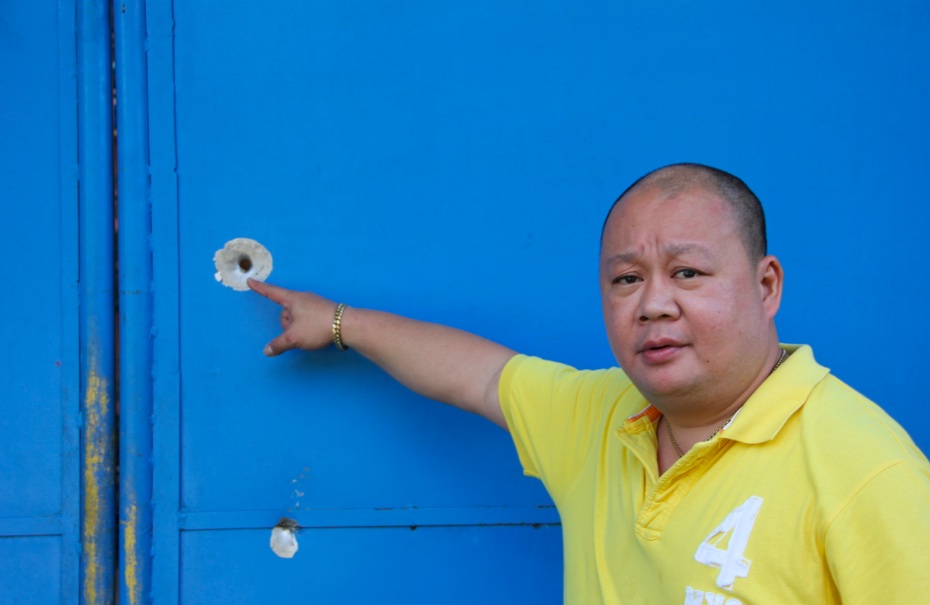 DIHUKUM.  Ofisial Comelec Wilfred Jay Balisado menunjukkan lubang peluru di gerbangnya di Kota Dipolog.  Foto oleh Gualberto Laput