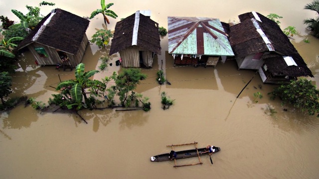 SUBMERGED. Residents ride a wooden boat as they paddle past submerged houses due to flooding brought about by heavy rains in the outskirts of Butuan City, Agusan del Sur province, January 13, 2014. Erwin Mascarinas/AFP