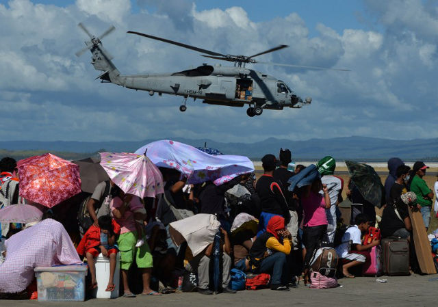 AIR SUPPORT. A US Navy helicopter flies over typhoon victims at Tacloban airport on November 15, 2013.  Photo by Mark Ralston/AFP
