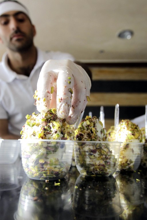 A TASTE OF DAMASCUS. An employee adds pistachios in cups of ice cream at a franchise of Syrian ice cream shop "Bakdash" that opened on Madina Munawwara Street in Jordan's capital, Amman on May 29, 2013. Photo by Khalil Mazraawi/AFP