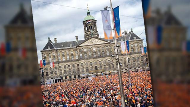 ORANGE COUNTRY. People, most of them wearing orange tee shirts, hats or plastic crowns, gather on April 30, 2013 at the Dam Square in Amsterdam, The Netherlands, to attend the investiture of the country's new King. Photo by AFP
