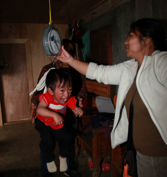 WEIGHT. A  barangay health worker weighs a child during a house visit in Brgy Topdac, Atok. Photo from Maria Dadiva Villanueva
