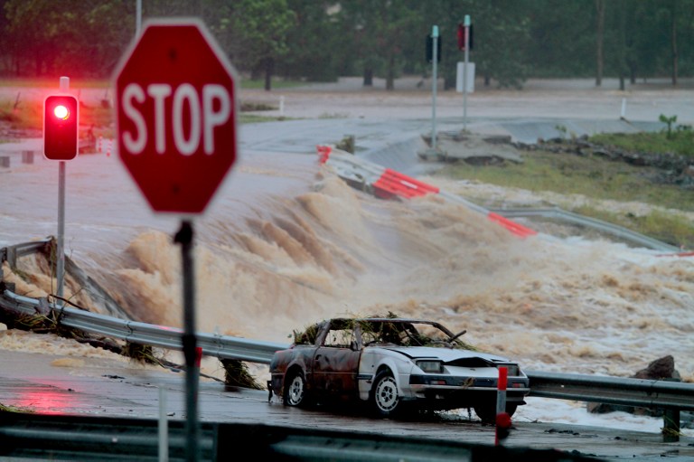 INUNDATED. Floodwaters race across the Oxenford - Tamborine road on Australia's Gold Coast on January 28, 2013 as severe floods swept through two states. AFP PHOTO / Brett Faulkner