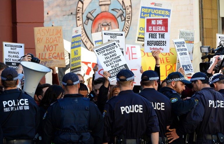 'LET THEM IN.' Police officers keep vigil as demonstrators shout slogans against the government's new policy of resettling refugees in Papua New Guinea as the ruling Labor party attended a caucus meeting in Sydney on July 22, 2013. Photo by AFP / Saeed Khan
