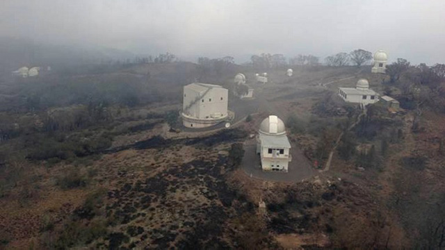This handout aerial picture taken on January 14, 2013 and provided by Rural Fire Service (RFS) of New South Wales shows the group of buildings at the Siding Spring Observatory, a remote global research facility in New South Wales, surrounded by burnt and smoldering ground after a fire raged through the night, fueled by hot, strong winds, damaging parts of the facility. AFP PHOTO / NSW Rural Fire Service