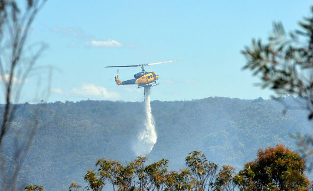 FIGHTING FIRE. A helicopter drops water to douse a fire in the Blue Mountains on October 24, 2013.  AFP PHOTO / Saeed KHAN