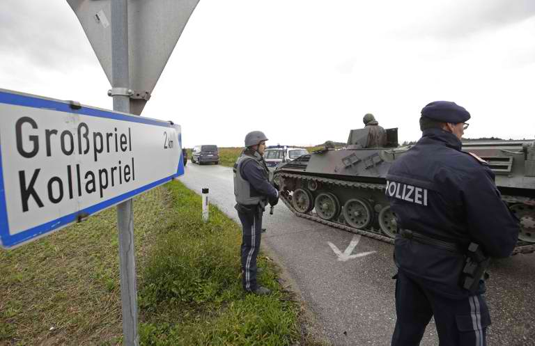 SECURITY ROADBLOCK. Policemen stand next to an armored vehicle of the Austrian army on September 17, 2013 on a road leading to Grosspriel, Austria, where a poacher has shut himself in a farmhouse with a hostage. AFP / Dieter Nagl