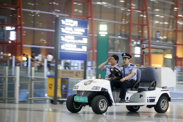 ON ALERT. Chinese police officers ride on an electric vehicle at the departures hall of Terminal 3 of the Beijing Capital Airport, 20 July 2013. Photo by EPA/Diego Azubel