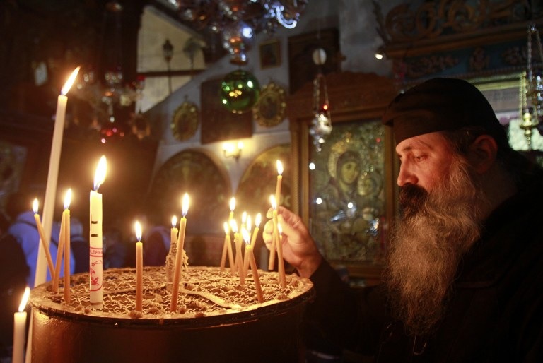 A CANDLE FOR CHRISTMAS. A Greek Orthodox priest lights a candle in the Church of the Nativity, traditionally believed to be the birthplace of Jesus Christ, as preparations for Christmas celebrations get underway in the West Bank biblical town of Bethlehem on December 23, 2013. AFP/Musa al-Shaer