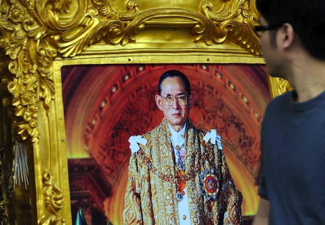 KING TURNS 86. A Thai man walks past a photograph of King Bhumibol Adulyadej kept for sale at a side street on the eve of his birthday in Bangkok on December 4, 2013. AFP/Indranil Mukherjee