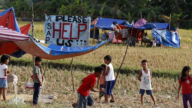 FOUR-LETTER WORD. A 'Help' sign is seen while Filipino children play outside their makeshift tents in rice fields drive following a 7.2-magnitude earthquake in Calape, Bohol, Philippines, 16 October 2013. EPA/Dennis Sabangan