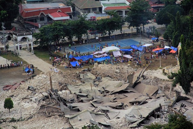 HOMELESS SURVIVORS. Victims of a huge earthquake in Loon, Bohol province stay in temporary tents next to the destroyed church in the town of Loon, Bohol province. Photo taken on October 16. AFP Photo/Philippine Air Force 