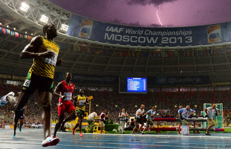 LIGHTNING & BOLT. Jamaica's Usain Bolt (L) wins the100 metres final at the 2013 IAAF World Championships at the Luzhniki stadium in Moscow on August 11, 2013 while a lightning strikes in the sky. Photo by AFP/Olivier Morin