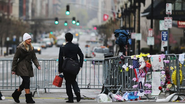 BOYLSTON STREET. People walk past a barricade and makeshift memorial blocking a still closed section of Boylston Street near the site of the Boston Marathon bombings on April 23, 2013 in Boston, Massachusetts. Business owners and residents of the closed section were allowed to return to their properties while under escort of city staff. Mario Tama/Getty Images/AFP
