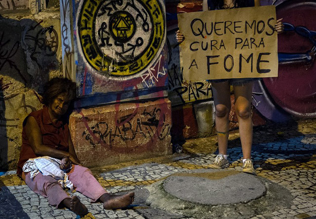 FIGHTING HUNGER. A protester stands next to a homeless woman with a placard reading "We want a cure for hunger" in the center of Recife, state of Pernambuco, Brazil, on June 20, 2013. File photo by Yasuyoshi Chiba/AFP