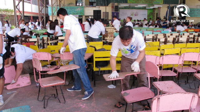HAND ON THE SAND. Volunteers smooth out the students’ desks with sandpaper before applying a fresh coat of paint. All photos by Donatela Manlongat/Rappler.com