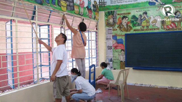 AIM HIGH. Volunteers use roller brushes to paint areas near the ceiling of an IRES classroom