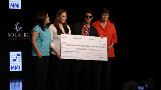 DONATION. Bruno Mars hands a check of $100,000 to ABS-CBN executives to be used in helping kids affected by Typhoon Yolanda