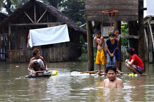 FLOODED. Residents gather next to a flooded basketball court at a village in Butuan City on January 17, 2014, as floods inundated villages and towns after heavy rains. Erwin Mascarinas/AFP