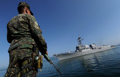 A Filipino soldier observes a US Navy ship. Photo by AFP