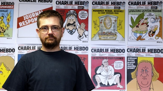 Penerbit dan pemimpin redaksi tabloid Charlie Hebdo, Stephane Charbonnier, berpose di depan karya komiknya di Paris, pada 27 Desember 2012. Charbonnier tewas pada 7 Januari 2015 saat kantornya diserang. Foto oleh AFP