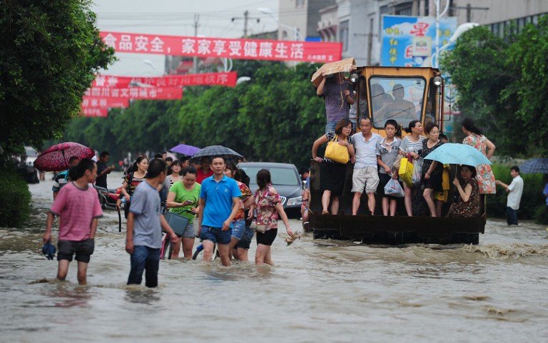 FLOODS IN CHENGDU. This picture taken on July 9, 2013 shows residents traveling on an excavator as others commute through flooded streets in a district in Chengdu, southwest China's Sichuan province. AFP Photo