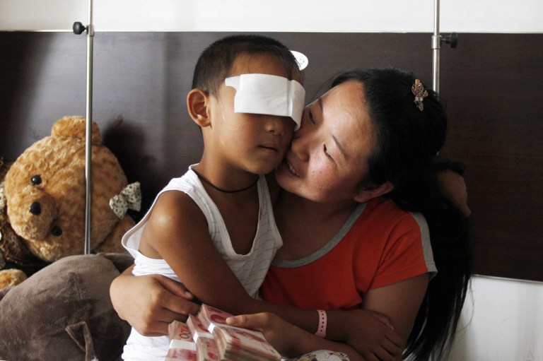 SURVIVOR. This picture taken on September 3, 2013 shows 6-year-old boy, Guo Bin, known as Bin-Bin (L), who was blinded when his eyes were gouged out August 24, being held by his mother as she accepts a donation in a hospital in Taiyuan, Shanxi province, China. AFP