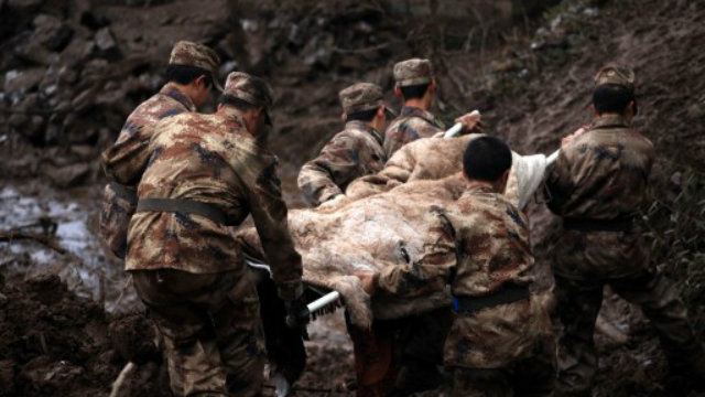 LANDSLIDE. Chinese rescue workers carry a dead body they found while searching for buried residents in a disaster-hit area in Gaopo village, southwest China's Yunnan province on January 11, 2013. Photo by AFP.