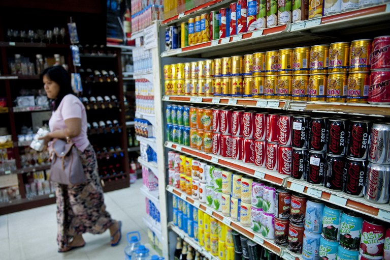 BACK IN MYANMAR. This picture taken on June 3, 2013 shows a woman walking past Coca-Cola cans sitting on a shelf at a supermarket in Yangon. Coca-Cola on June 4 opened a factory in Myanmar as it returns to the former pariah state after an absence of more than six decades. Photo by Ye Aung Thu/AFP