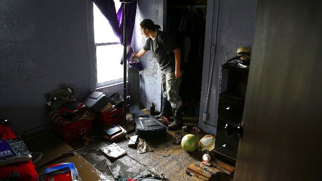 DAMAGED. Julie DeGraff pulls back a curtain to reveal the damage inside her home, which had upwards of a foot of standing water inside, on September 14, 2013 in La Salle, Colorado. Photo by  Agence France-Presse