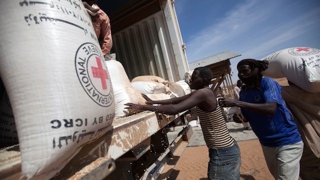 FOOD AID. In this photo, community members at the Nifasha IDP camp in North Darfur unload bags of sorghum from a WFP truck, 11 February 2014, in Shangil Tobaya, Sudan. Albert González Farran/UN Photo