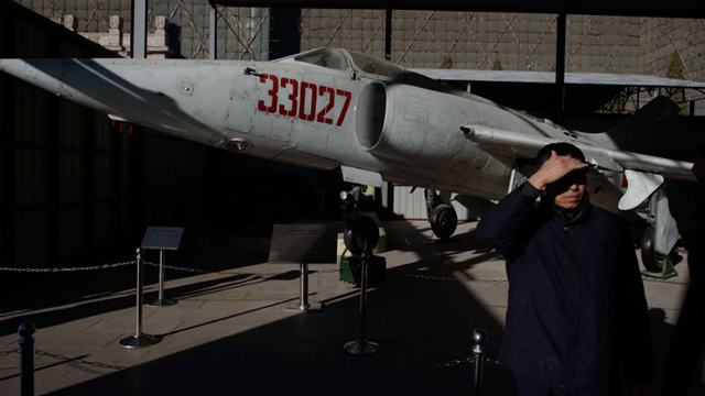 AIR DEFENSE. A visitor stands before a decommissioned Chinese A-5 Ground Attack aircraft at the Military Museum in Beijing on November 28, 2013. Ed Jones/AFP Photo