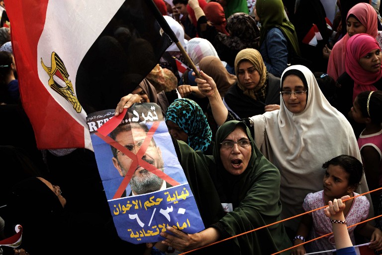ANTI-MORSI CROWD. Opposition protesters shout slogans and show a defaced poster of their president as they gather in thousands at the Presidential Palace to protest against Egyptian President Mohamed Morsi and the Muslim Brotherhood on July 2 in Cairo. Photo by AFP/Gianluigi Guercia