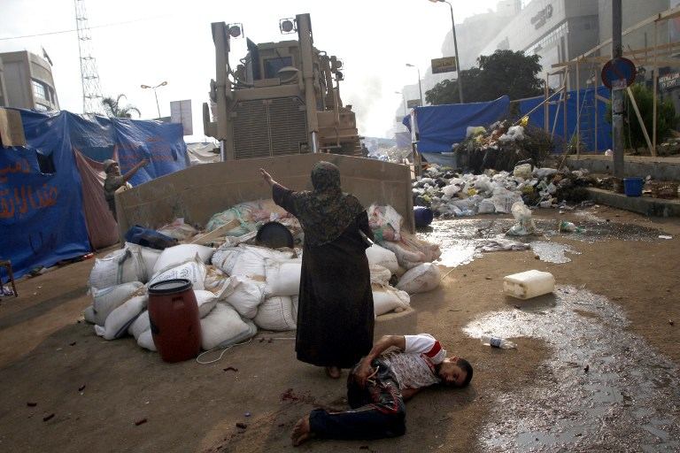 ECHOES OF TIANANMEN. An Egyptian woman tries to stop a military bulldozer from hurting a wounded youth during clashes that broke out as Egyptian security forces moved in to disperse supporters of Egypt's deposed president Mohamed Morsi in a huge protest camp near Rabaa al-Adawiya mosque in eastern Cairo on August 14, 2013.  Photo by AFP/ Mohammed Abdel Moneim