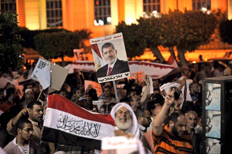 PRO-MORSI RALLY. Egyptian supporters of the deposed president Mohamed Morsi hold his portrait and wave the national flags during a demonstration against the government in Cairo on July 31, 2013. Photo by AFP/Fayez Nureldine