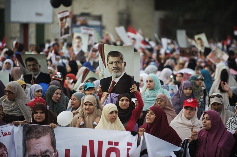 FOR MORSI. Egyptian women from the Muslim Brotherhood hold portraits of ousted President Mohammed Morsi as they march in his support on August 11, 2013 in Cairo. Photo by AFP / Gianluigi Guercia