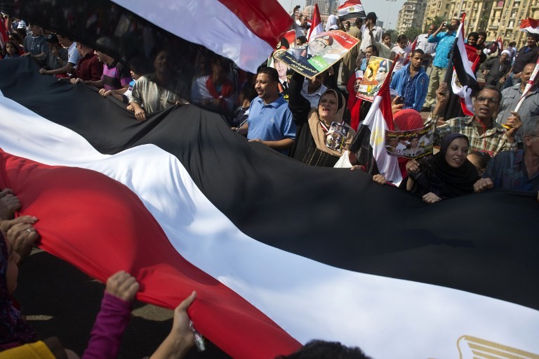 NEW EGYPT PROTESTS. Egyptians wave a giant national flag on Tahrir Square as they mark the 40th anniversary of the 1973 Arab-Israeli war on October 6, 2013 in the Egyptian capital Cairo. AFP / Khaled Desouki
