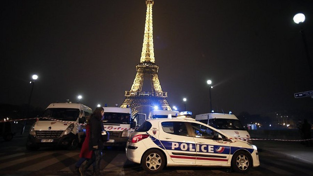 SECURITY. People walk past police cars blocking the Eiffel Tower in Paris following an anonymous phone call announcing an attack. Photo from AFP