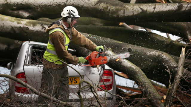 HEAVY DAMAGE. A worker with a chain saw cuts branches of a tree that landed on a car after a powerful Atlantic storm made landfall in Davidsons Mains, Edinburgh, Scotland. Photo from EPA/David Cheskin
