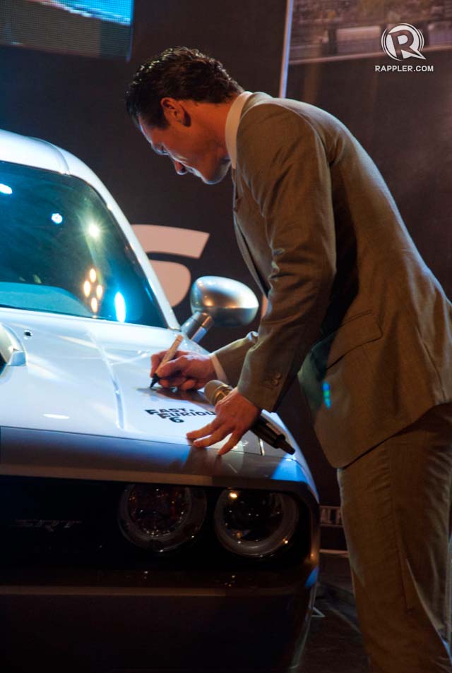 AUTOGRAPHED SPORTSCAR. Luke Evans signs the Chrysler Dodge to be auctioned off for charity