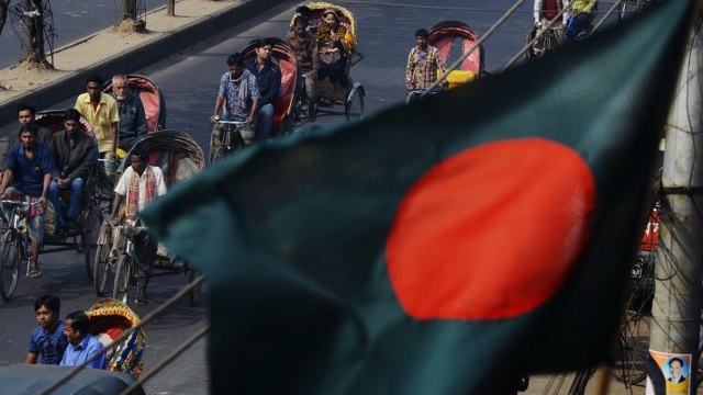 DHAKA COMMUTE. A Bangladeshi flag flutters in the wind as cycle rickshaw drivers ferry commuters down an avenue in Dhaka on January 4, 2014. Roberto Schmidt/AFP