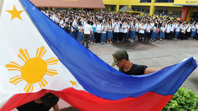 RAISE THE FLAG. Hundreds of students join a flag ceremony to sing the national anthem at a public school. Photo by Jay Directo/AFP