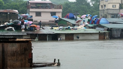 VIEW FROM THE TOP. Residents view their flooded neighborhood from the roof of their houses. Photo by Maurits Van Linder