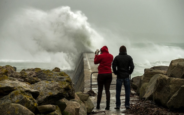 DANGER AHEAD. Two people look on as big waves crash against a break-water pier during a storm in Esquibien, in the Western region of Brittany, France, 23 December 2013. EPA/Ian Langsdon