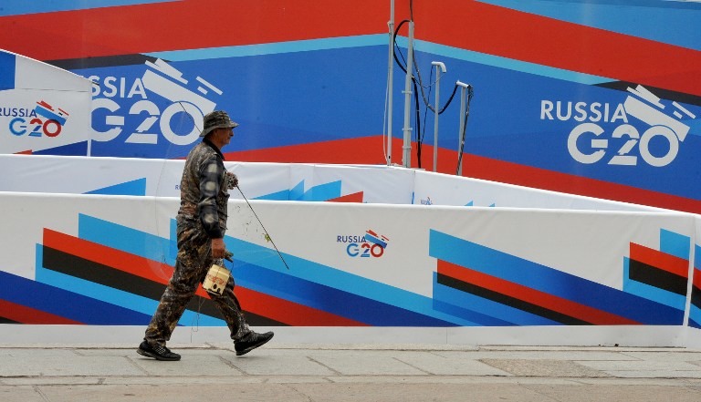 G20 IN RUSSIA. A man walks past the posters promoting G20 summit in St.Petersburg, on September 2, 2013. AFP / Olga Maltseva