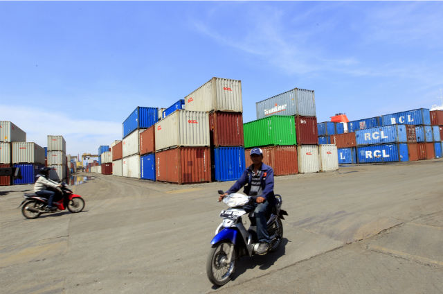 COMPETITIVE? An Indonesian rides a motorbike past containers at the Tanjung Priok Port in Jakarta, Indonesia, in this 2012 file photo. Photo by Bagus Indahono/EPA