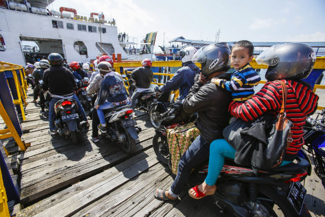 A family of 3 on a motorcycle waits to board a passenger ship at Gilimanuk Port in Jembrana, Bali, on July 24, 2014. Photo by EPA